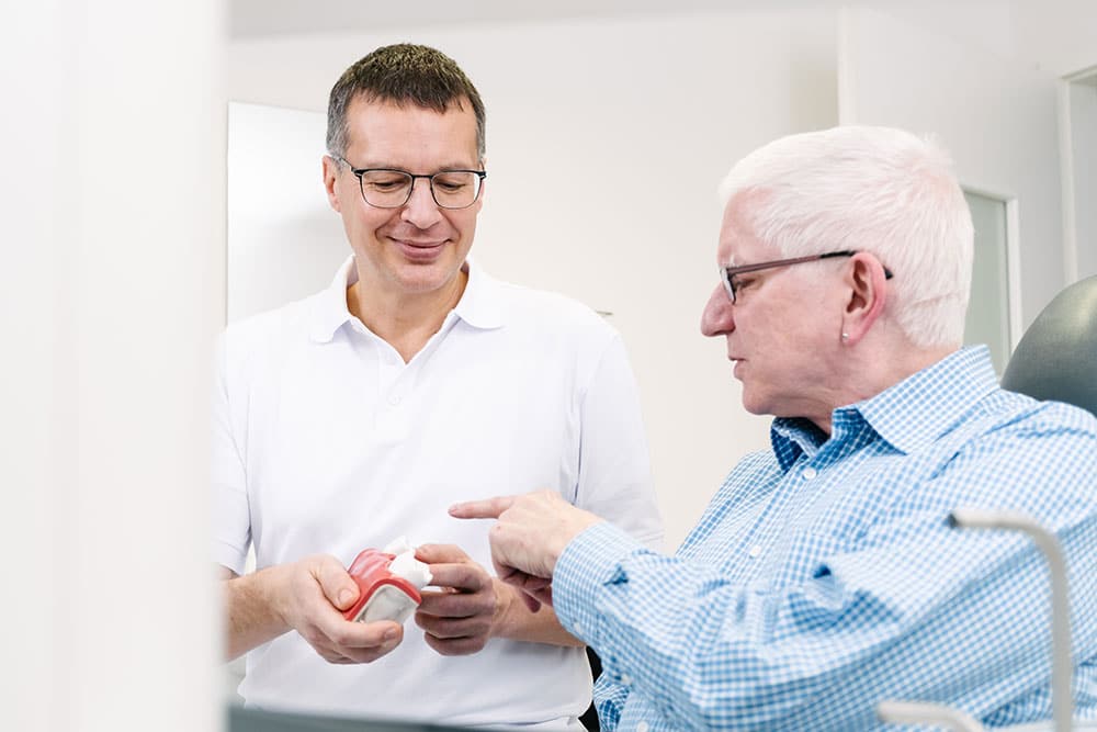 Zahnarzt Pinneberg Dr. Philip Kummerer behandelt einen Patient und beantwortet Fragen rund um ein implantat